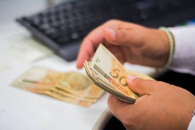 Değişim bürosu / bankada çalışan iş adamının insan eli. O para sayıyor ve bir müşteriye nakit para veriyor. Brezilyalı 50 reais fatura.