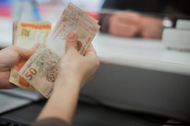 Değişim bürosu / bankada çalışan iş adamının insan eli. O para sayıyor ve bir müşteriye nakit para veriyor. Brezilyalı Reais.