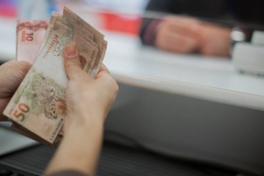 Değişim bürosu / bankada çalışan iş adamının insan eli. O para sayıyor ve bir müşteriye nakit para veriyor. Brezilyalı Reais.