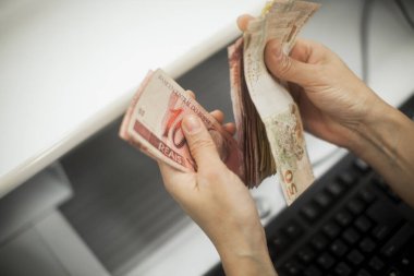 Değişim bürosu / bankada çalışan iş adamının insan eli. O para sayıyor ve bir müşteriye nakit para veriyor. Brezilyalı Reais.