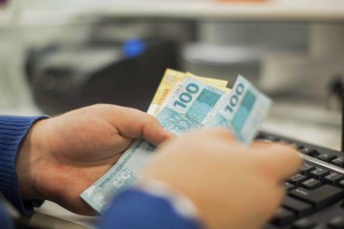 Değişim bürosu / bankada çalışan iş adamının insan eli. O para sayıyor ve bir müşteriye nakit para veriyor. Brezilya Reais 100 reais.