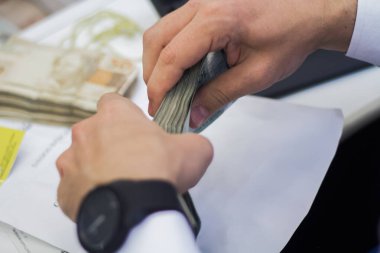 Değişim bürosu / bankada çalışan iş adamının insan eli. O para sayıyor ve bir müşteriye nakit para veriyor. Brezilyalı 50 reais fatura.