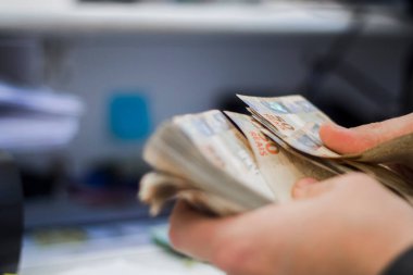 Değişim bürosu / bankada çalışan iş adamının insan eli. O para sayıyor ve bir müşteriye nakit para veriyor. Brezilyalı 50 reais fatura.