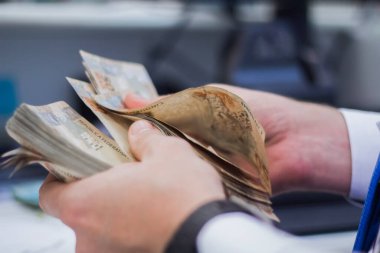 Değişim bürosu / bankada çalışan iş adamının insan eli. O para sayıyor ve bir müşteriye nakit para veriyor. Brezilyalı 50 reais fatura.