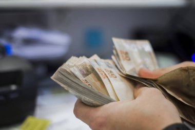 Değişim bürosu / bankada çalışan iş adamının insan eli. O para sayıyor ve bir müşteriye nakit para veriyor. Brezilyalı 50 reais fatura.