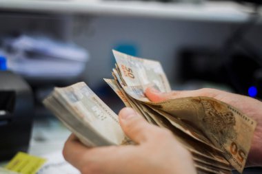 Değişim bürosu / bankada çalışan iş adamının insan eli. O para sayıyor ve bir müşteriye nakit para veriyor. Brezilyalı 50 reais fatura.