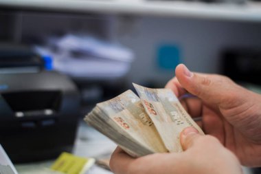 Değişim bürosu / bankada çalışan iş adamının insan eli. O para sayıyor ve bir müşteriye nakit para veriyor. Brezilyalı 50 reais fatura.