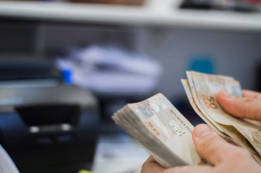 Değişim bürosu / bankada çalışan iş adamının insan eli. O para sayıyor ve bir müşteriye nakit para veriyor. Brezilyalı 50 reais fatura.