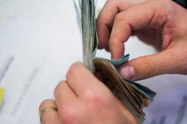 Değişim bürosu / bankada çalışan iş adamının insan eli. O para sayıyor ve bir müşteriye nakit para veriyor. Brezilyalı Reais.