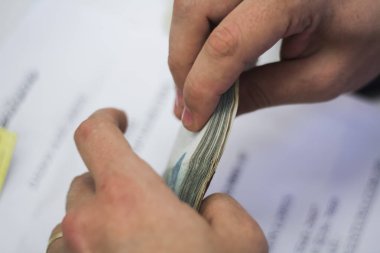 Değişim bürosu / bankada çalışan iş adamının insan eli. O para sayıyor ve bir müşteriye nakit para veriyor. Brezilyalı Reais.