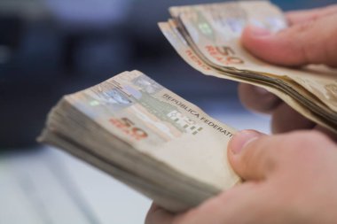 Değişim bürosu / bankada çalışan iş adamının insan eli. O para sayıyor ve bir müşteriye nakit para veriyor. Brezilyalı 50 reais fatura.