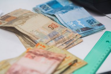 Değişim bürosu / bankada çalışan iş adamının insan eli. O para sayıyor ve bir müşteriye nakit para veriyor. Brezilyalı Reais.