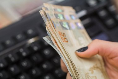 Değişim bürosu / bankada çalışan iş adamının insan eli. O para sayıyor ve bir müşteriye nakit para veriyor. Brezilyalı 50 reais fatura.