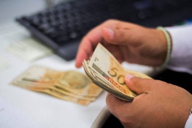 Değişim bürosu / bankada çalışan iş adamının insan eli. O para sayıyor ve bir müşteriye nakit para veriyor. Brezilyalı 50 reais fatura.