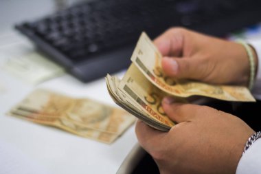 Değişim bürosu / bankada çalışan iş adamının insan eli. O para sayıyor ve bir müşteriye nakit para veriyor. Brezilyalı 50 reais fatura.