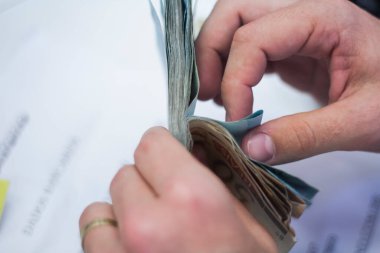 Değişim bürosu / bankada çalışan iş adamının insan eli. O para sayıyor ve bir müşteriye nakit para veriyor. Brezilyalı Reais.