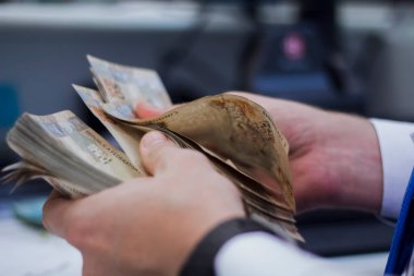 Değişim bürosu / bankada çalışan iş adamının insan eli. O para sayıyor ve bir müşteriye nakit para veriyor. Brezilyalı 50 reais fatura.