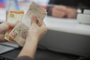 Değişim bürosu / bankada çalışan iş adamının insan eli. O para sayıyor ve bir müşteriye nakit para veriyor. Brezilyalı Reais.