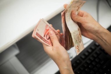 Değişim bürosu / bankada çalışan iş adamının insan eli. O para sayıyor ve bir müşteriye nakit para veriyor. Brezilyalı Reais.