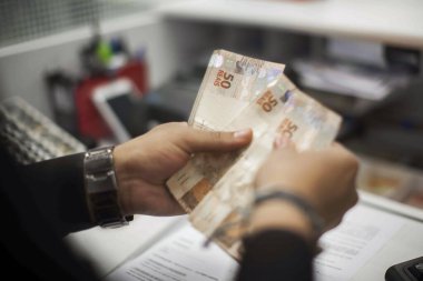 Değişim bürosu / bankada çalışan iş adamının insan eli. O para sayıyor ve bir müşteriye nakit para veriyor. Brezilyalı 50 reais fatura.