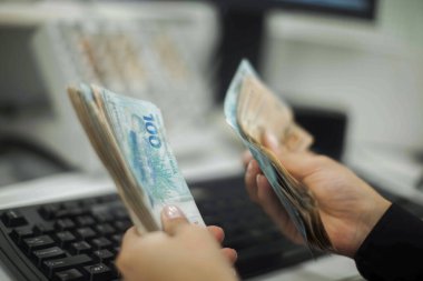 Değişim bürosu / bankada çalışan iş adamının insan eli. O para sayıyor ve bir müşteriye nakit para veriyor. Brezilyalı Reais.