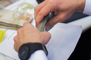 Değişim bürosu / bankada çalışan iş adamının insan eli. O para sayıyor ve bir müşteriye nakit para veriyor. Brezilyalı 50 reais fatura.
