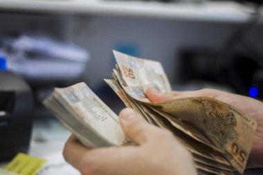 Değişim bürosu / bankada çalışan iş adamının insan eli. O para sayıyor ve bir müşteriye nakit para veriyor. Brezilyalı 50 reais fatura.