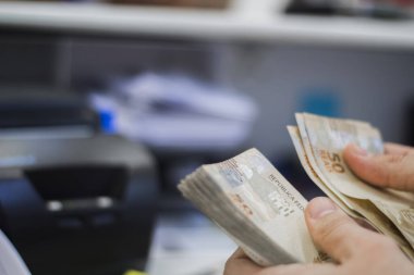 Değişim bürosu / bankada çalışan iş adamının insan eli. O para sayıyor ve bir müşteriye nakit para veriyor. Brezilyalı 50 reais fatura.