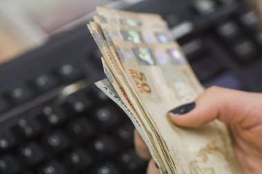 Değişim bürosu / bankada çalışan iş adamının insan eli. O para sayıyor ve bir müşteriye nakit para veriyor. Brezilyalı 50 reais fatura.
