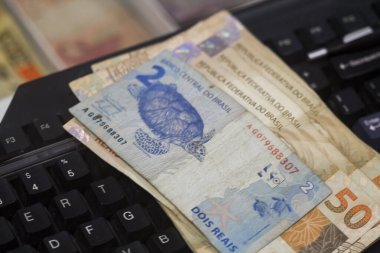 Değişim bürosu / bankada çalışan iş adamının insan eli. O para sayıyor ve bir müşteriye nakit para veriyor. Brezilyalı Reais.