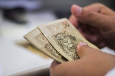 Değişim bürosu / bankada çalışan iş adamının insan eli. O para sayıyor ve bir müşteriye nakit para veriyor. Brezilyalı 50 reais fatura.