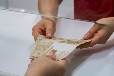 Değişim bürosu / bankada çalışan iş adamının insan eli. O para sayıyor ve bir müşteriye nakit para veriyor. Brezilyalı 50 reais fatura.