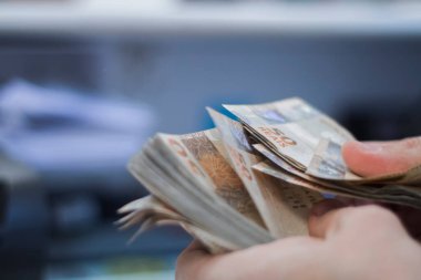 Değişim bürosu / bankada çalışan iş adamının insan eli. O para sayıyor ve bir müşteriye nakit para veriyor. Brezilyalı 50 reais fatura.