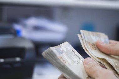 Değişim bürosu / bankada çalışan iş adamının insan eli. O para sayıyor ve bir müşteriye nakit para veriyor. Brezilyalı 50 reais fatura.