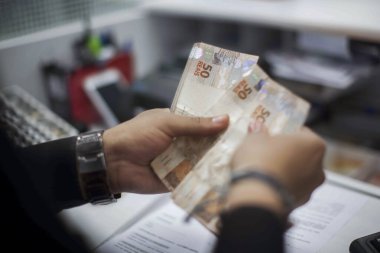 Değişim bürosu / bankada çalışan iş adamının insan eli. O para sayıyor ve bir müşteriye nakit para veriyor. Brezilyalı 50 reais fatura.