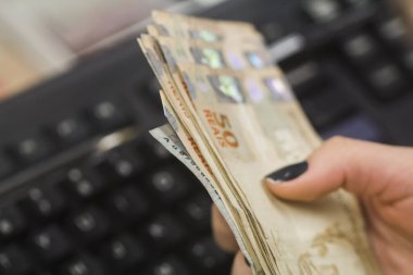 Değişim bürosu / bankada çalışan iş adamının insan eli. O para sayıyor ve bir müşteriye nakit para veriyor. Brezilyalı 50 reais fatura.