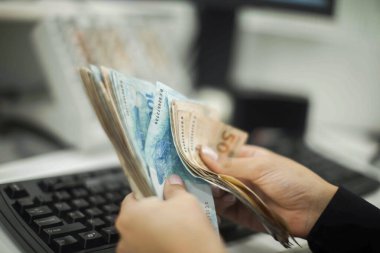 Değişim bürosu / bankada çalışan iş adamının insan eli. O para sayıyor ve bir müşteriye nakit para veriyor. Brezilyalı Reais.