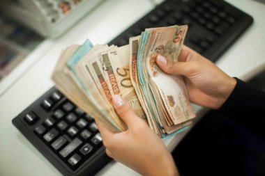 Değişim bürosu / bankada çalışan iş adamının insan eli. O para sayıyor ve bir müşteriye nakit para veriyor. Brezilyalı 50 reais fatura.