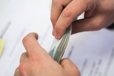 Değişim bürosu / bankada çalışan iş adamının insan eli. O para sayıyor ve bir müşteriye nakit para veriyor. Brezilyalı Reais.