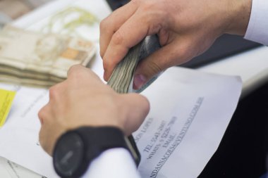 Değişim bürosu / bankada çalışan iş adamının insan eli. O para sayıyor ve bir müşteriye nakit para veriyor. Brezilyalı Reais.