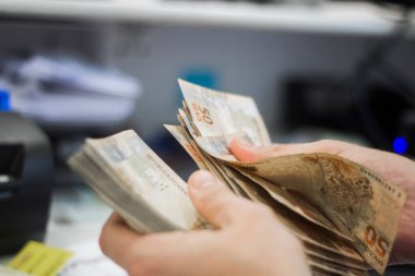 Değişim bürosu / bankada çalışan iş adamının insan eli. O para sayıyor ve bir müşteriye nakit para veriyor. Brezilyalı 50 reais fatura.