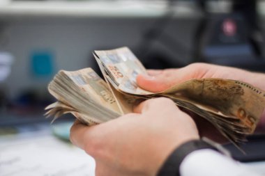 Değişim bürosu / bankada çalışan iş adamının insan eli. O para sayıyor ve bir müşteriye nakit para veriyor. Brezilyalı 50 reais fatura.