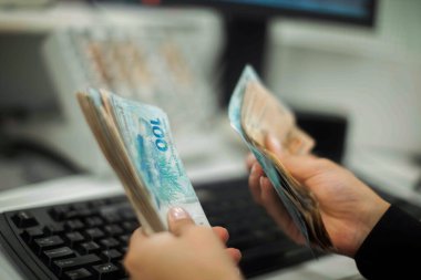 Değişim bürosu / bankada çalışan iş adamının insan eli. O para sayıyor ve bir müşteriye nakit para veriyor. Brezilya Reais 100 reais.
