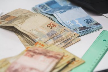 Değişim bürosu / bankada çalışan iş adamının insan eli. O para sayıyor ve bir müşteriye nakit para veriyor. Brezilyalı Reais.