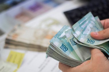 Değişim bürosu / bankada çalışan iş adamının insan eli. O para sayıyor ve bir müşteriye nakit para veriyor. Brezilya Reais 100 reais.