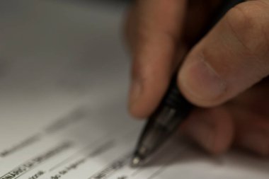 Gündüz vakti masa başında kalem imzalayan bir iş adamının ekili fotoğrafı..