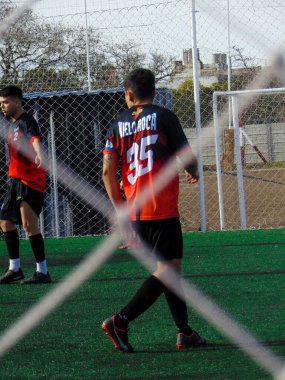 Güneşli bir günde sentetik çim tarlasında futbol oynayan insanlar
