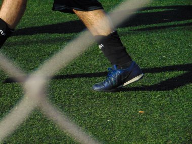 Güneşli bir günde sentetik çim tarlasında futbol oynayan insanlar