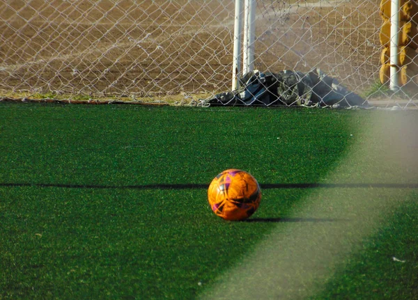 合成草のピッチのオレンジサッカーボール — ストック写真