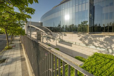 Çelik ve camla kaplı bir ofis binasının ön cephesinin yanındaki çelik korkuluklar.